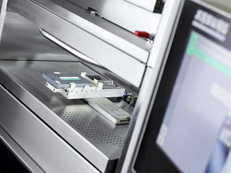 Ein in eine vernetzte Industrie-4.0-Anwendung integrierter Freeformer individualisiert „smarte“ Kofferanhänger, indem er ein- oder zweifarbige 3D-Grafiken aufbringt. Die zugehörigen Auftragsdaten werden aus dem NFC-Chip im Bauteil ausgelesen. (Foto: Arburg)