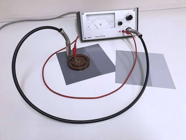 Messung des Oberflächenwiderstandes an lackierter PVC-Bahnenware mittels Teraohm-Meter und Ringelektrode. Linke Seite jeweils mit Rowakryl G-34747W lackiert, rechte Seite unlackiert. (Foto: Rowa)