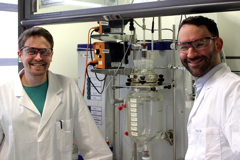 Paul Stockmann und Dr. Van Opdenbosch mit dem Reaktor, in dem das polymerisationsfähigen Monomer aus dem Naturstoff 3-Caren hergestellt wurde. (Foto: C. Zollfrank / TUM)
