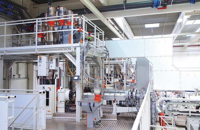 Die 7-Schicht-Folienanlage ist in drei Funktionsebenen übereinander aufgebaut. Auf der untersten Ebene (hier nicht sichtbar) befinden sich drei Extruder (siehe Abb.3), auf Ebene zwei befinden sich die zwei Extruder für die Deckschichten, auf der obersten Ebene die Dosiergeräte zur Versorgung der darunter befindlichen Extruder. (Foto: Motan)