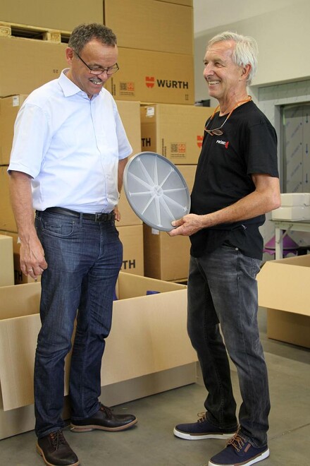Joachim Fröbel zeigt Erwin Neugebauer von Wittmann Battenfeld den auf der 2-Komponenten MacroPower gefertigten Boden für einen Hocker. (Foto: Wittmann Battenfeld)