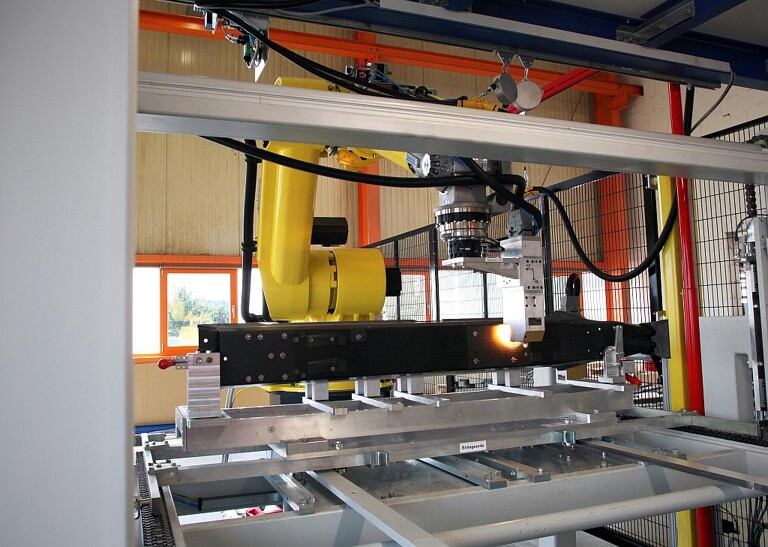 Roboter im Arbeitsprozess „Bolzen kleben“, Bauteil wird an der Bolzenposition erwärmt. (Foto: Reis)