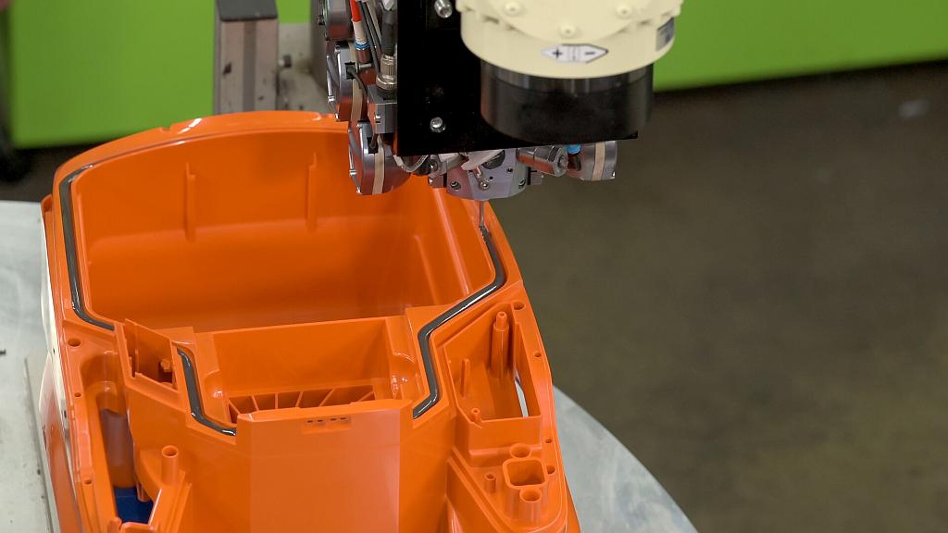 Der am 6-Achs-Roboter montierte Mischkopf appliziert 2K Polyurethanschaum zum Abdichten des Staubsaugergehäuses in die Nut. (Foto: Henkel)