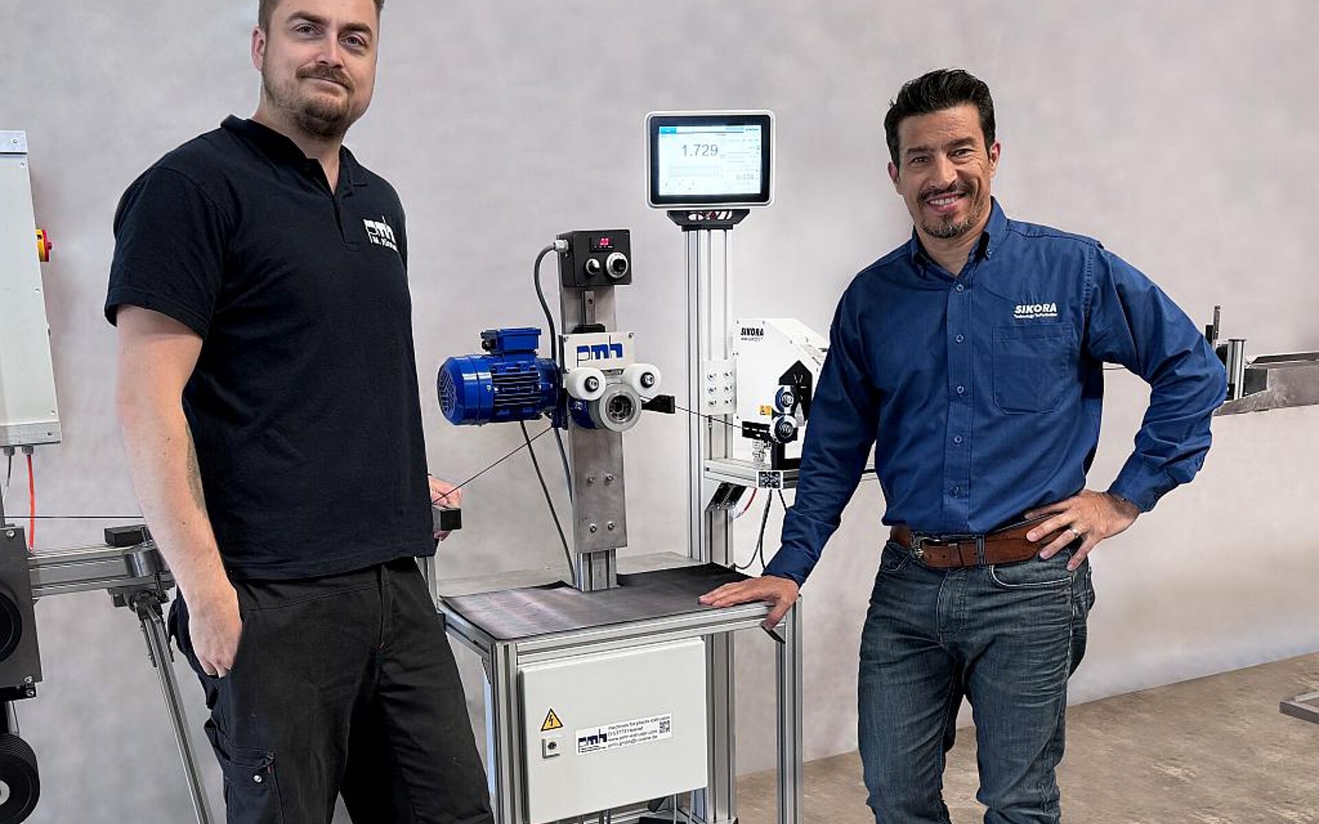 Michael Kinnart (l.), technischer Leiter bei PMH, mit Aguinaldo Ramalho, Head of Sales Wire & Cable, an der Filamentanlage mit dem integrierten Durchmessermesskopf und Knotendetektor Laser Lump. (Foto: Sikora)