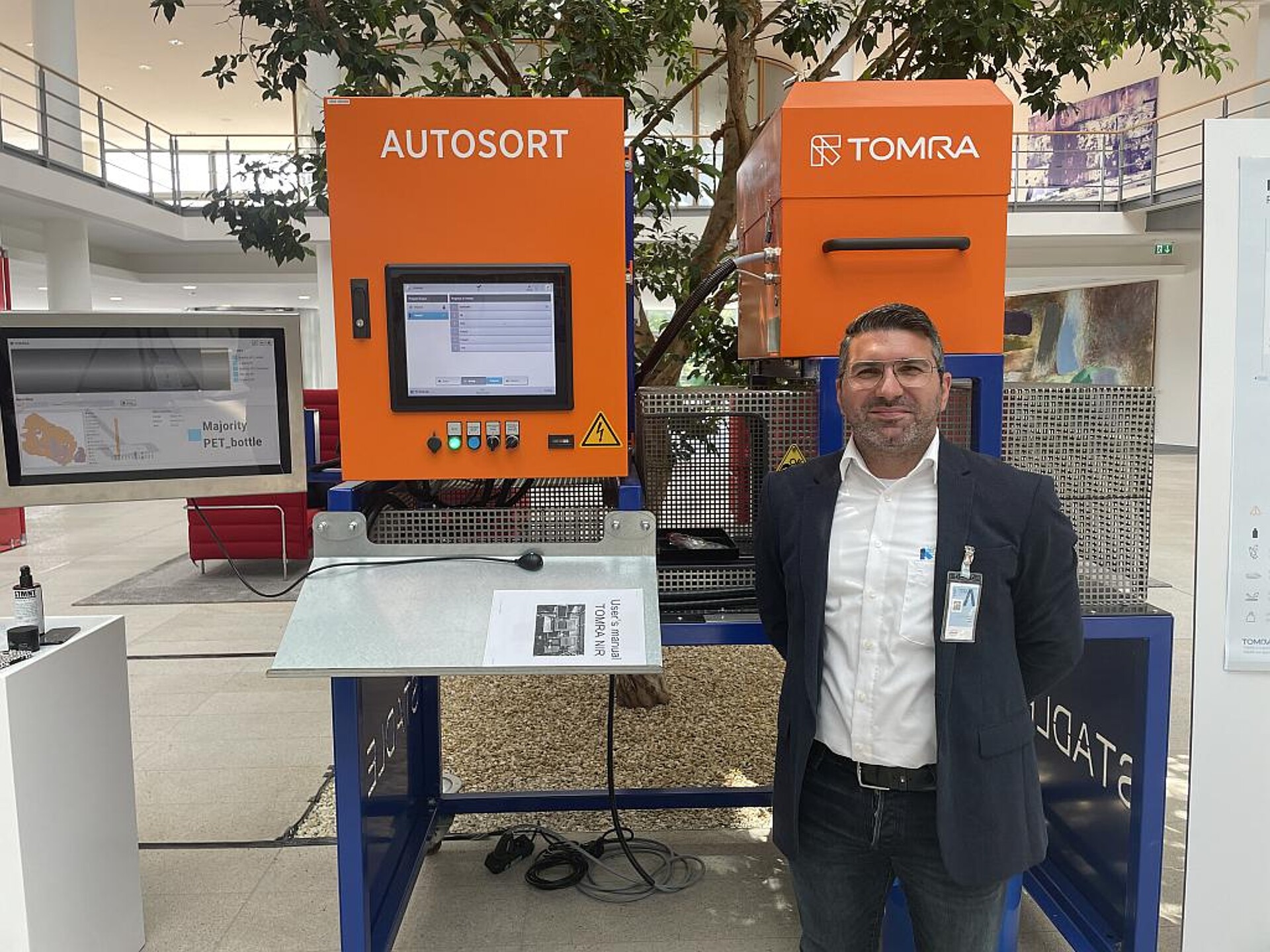 Valerio Sama, Markt Strategie Manager – Verpackungen bei Tomra Recycling, präsentiert den Henkel-Mitarbeitern den Autosort-Scanner. (Foto: Tomra)