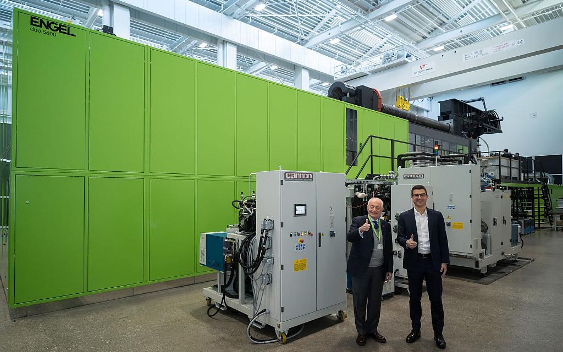 Marco Volpato (l.), Präsident und Vorstandsvorsitzender der Cannon Group, und Stefan Engleder (r.), CEO der Engel Group, vor der weltweit größten Spritzgießzelle mit PUR-Anlage in einem Technikum. (Foto: Engel)