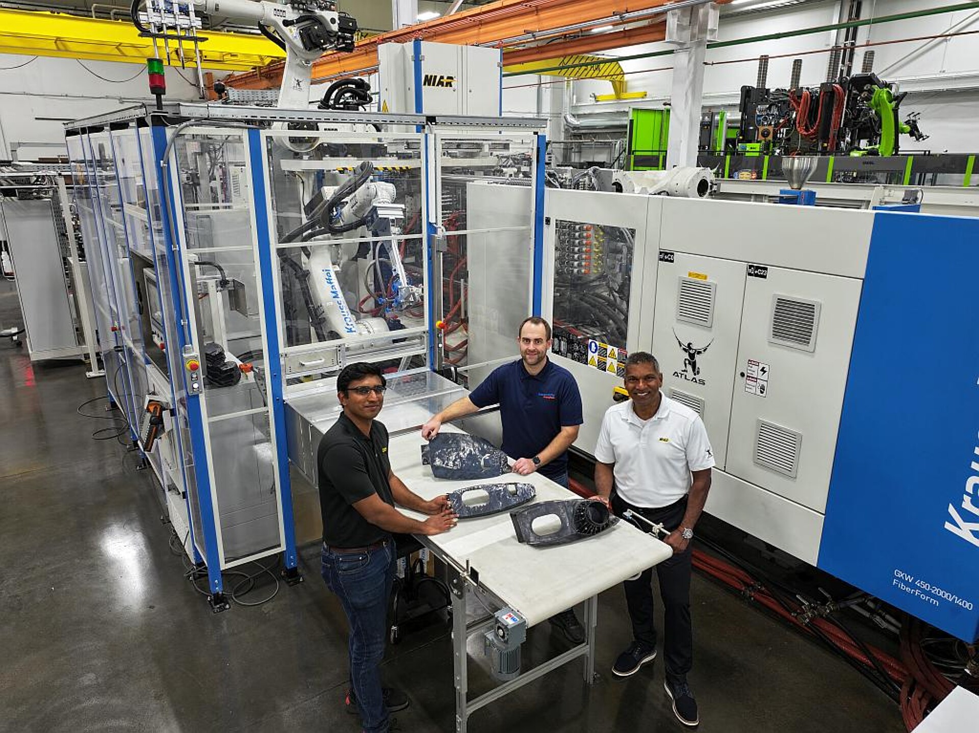 Treiben gemeinsam die Entwicklung des thermoplastischen Leichtbaus in der Luftfahrt voran (v. l.): Induwara Herath (Research Engineer, NIAR ATLAS, Eugen Schubert (Sales and Applications Manager, IMM & Automation bei KraussMaffei) und Dr. Waruna Seneviratne (Leiter NIAR ATLAS) vor der GXW 450 FiberForm im NIAR ATLAS Labor. (Foto: KraussMaffei)