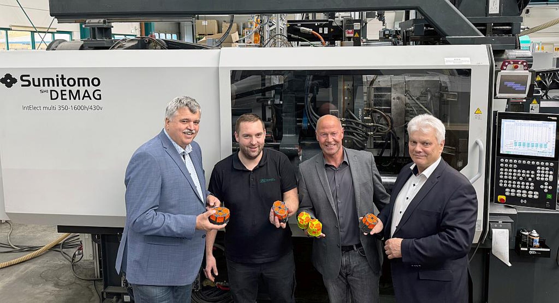 Jürgen Burkert (Geschäftsführer HSK), Mathias Grimm (Leiter Werk 2 HSK), Ralf Schiefer (Head of Strategic Business + Product Development HSK) sowie Dr. Gerald Fiedler (Vertriebsingenieur Sumitomo (SHI) Demag, v.l.n.r.) an einer IntElect Multi 300 für das 2K-Spritzgießen. (Foto: Sumitomo (SHI) Demag)
