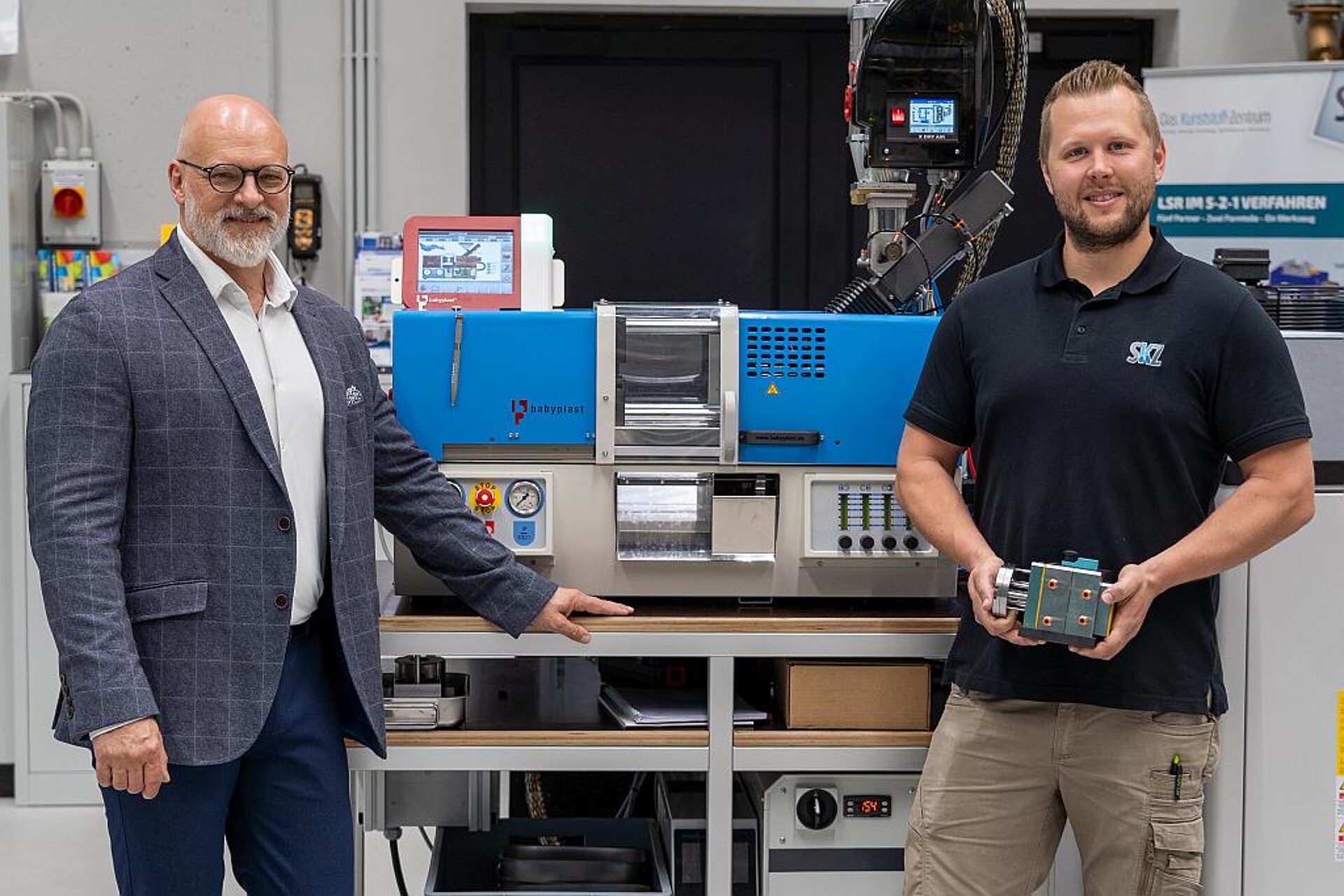 Marc Tesche (l.), Geschäftsführer Christmann Kunststofftechnik, und Christoph Mussauer (r.), Leitung Spritzgießtechnikum, vor der neuen SKZ-Maschine mit einem ersten Werkzeug. (Foto: Luca Hoffmannbeck/SKZ)