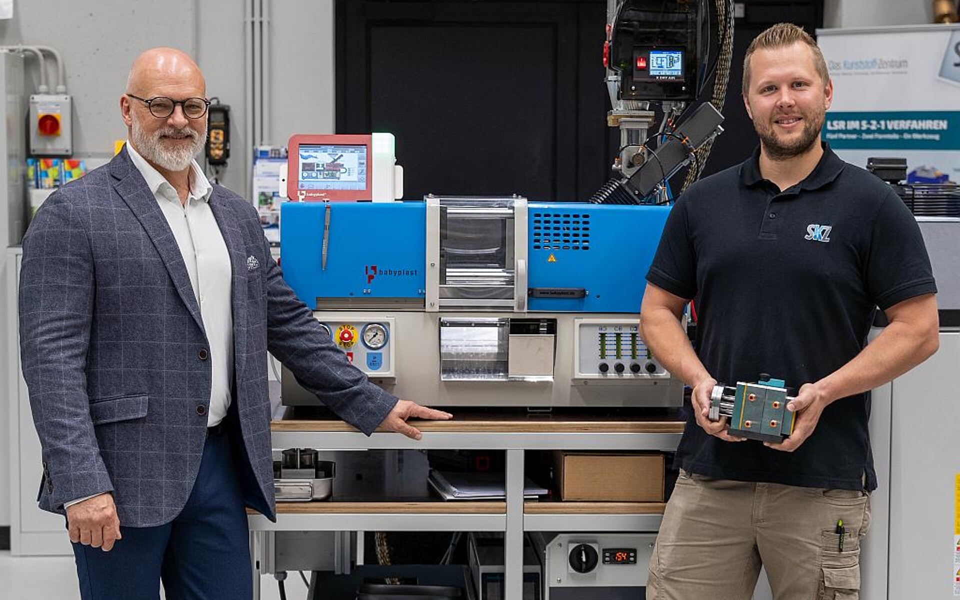 Marc Tesche (l.), Geschäftsführer Christmann Kunststofftechnik, und Christoph Mussauer (r.), Leitung Spritzgießtechnikum, vor der neuen SKZ-Maschine mit einem ersten Werkzeug. (Foto: Luca Hoffmannbeck/SKZ)