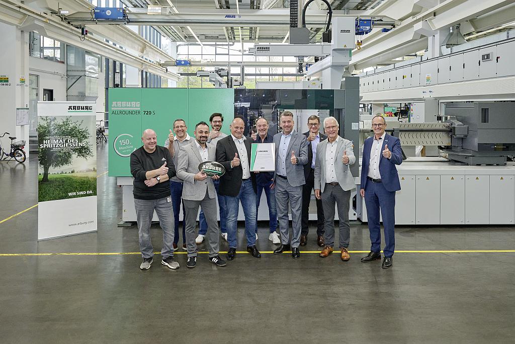 Stolz auf 50 Jahre Kooperation und die Übergabe des 150. Allrounders: Tobias Baur (4. v. r.), Arburg-Geschäftsführer Vertrieb und Aftersales, und Christian Abicht (5. v. l.), Geschäftsführer HK Cosmetic Packaging, mit ihren Teams. (Foto: Arburg)